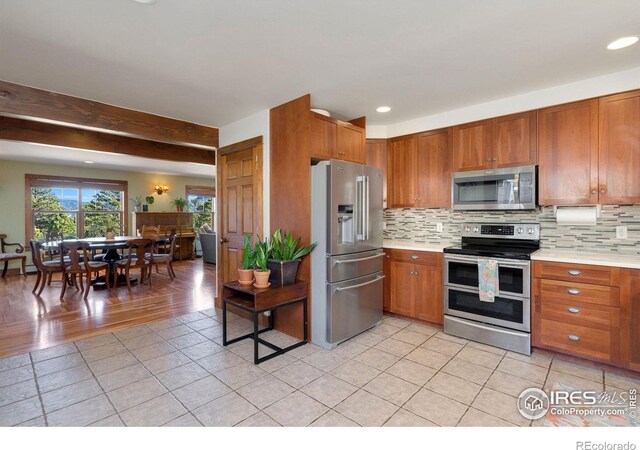 kitchen with decorative backsplash, light tile patterned floors, and stainless steel appliances