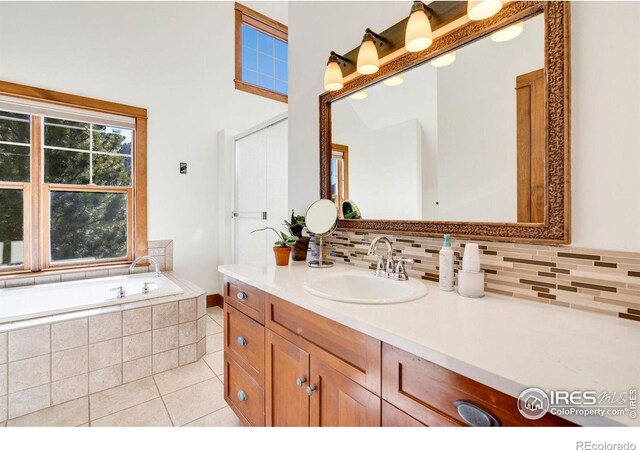 bathroom featuring tile patterned floors, vanity, decorative backsplash, and tiled tub