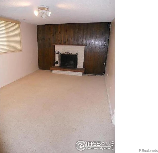 unfurnished living room featuring a brick fireplace and wooden walls