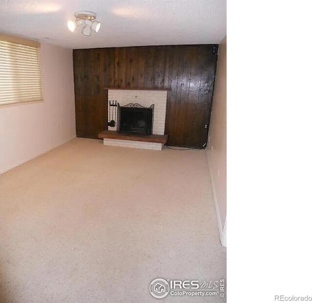 unfurnished living room featuring a fireplace, light colored carpet, and wooden walls