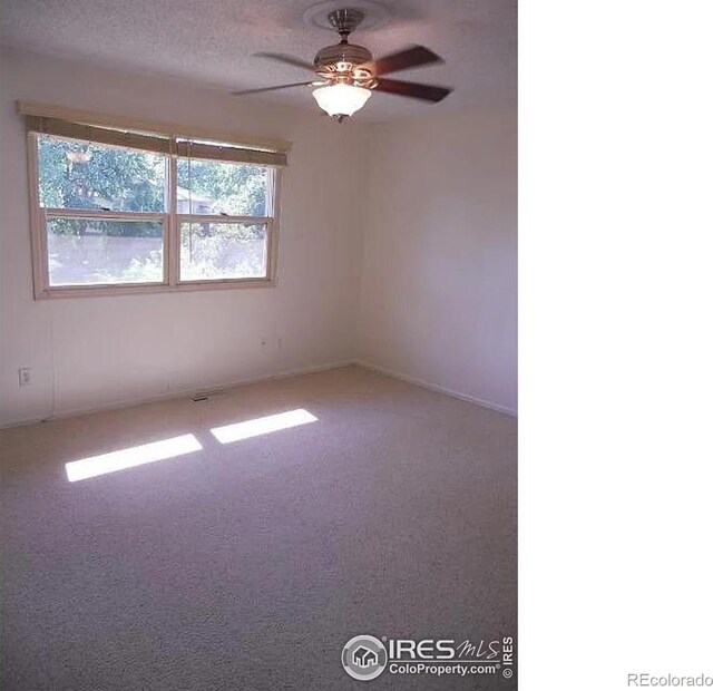 carpeted spare room featuring ceiling fan and a textured ceiling