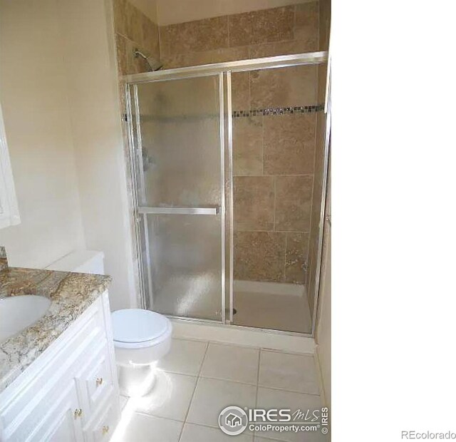 bathroom with tile patterned floors, vanity, an enclosed shower, and toilet