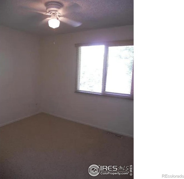 carpeted spare room featuring ceiling fan and a textured ceiling