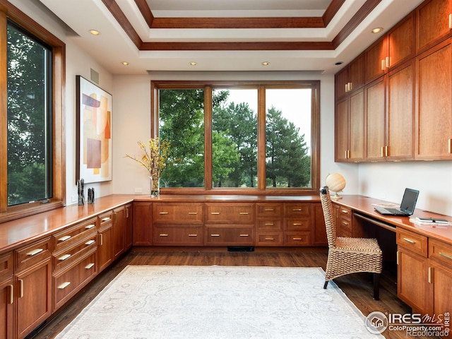 office featuring ornamental molding, recessed lighting, built in desk, a tray ceiling, and dark wood finished floors