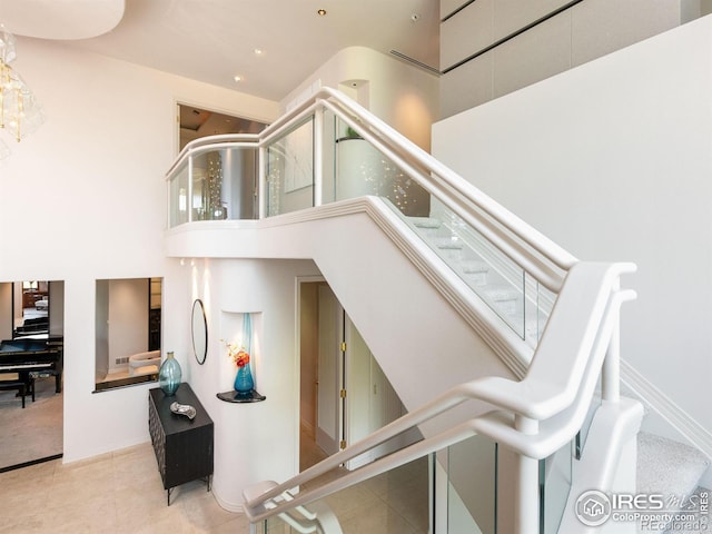 stairs featuring baseboards, tile patterned flooring, and a high ceiling