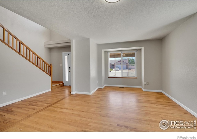 empty room with light hardwood / wood-style floors and a textured ceiling