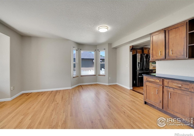 kitchen with fridge with ice dispenser, light hardwood / wood-style floors, and a textured ceiling