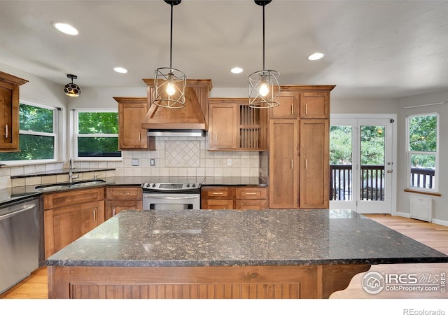 kitchen featuring stainless steel appliances, sink, pendant lighting, and a center island