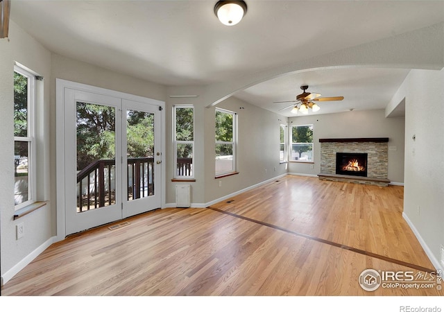 unfurnished living room featuring a fireplace, a wealth of natural light, ceiling fan, and light wood-type flooring