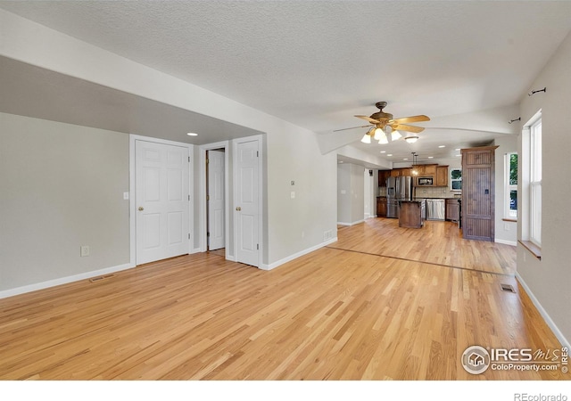 unfurnished living room featuring light wood-type flooring, a textured ceiling, and ceiling fan