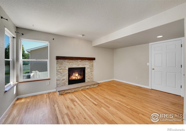 unfurnished living room featuring a textured ceiling, hardwood / wood-style flooring, and a fireplace