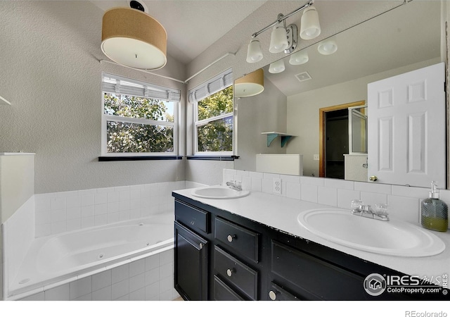 bathroom with vanity and tiled tub