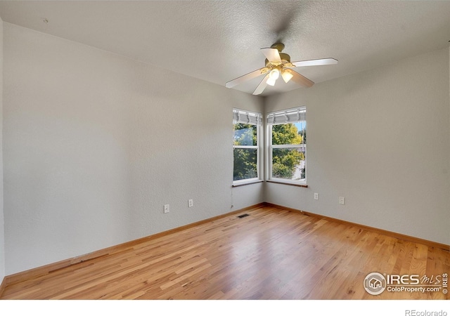 unfurnished room with ceiling fan, a textured ceiling, and light wood-type flooring