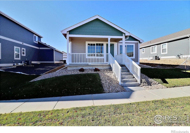 view of front of home featuring central AC unit, a porch, and a front yard