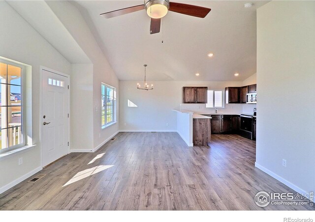 interior space with ceiling fan with notable chandelier, light hardwood / wood-style flooring, and vaulted ceiling