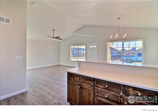 kitchen with plenty of natural light, light wood-type flooring, lofted ceiling, and decorative light fixtures