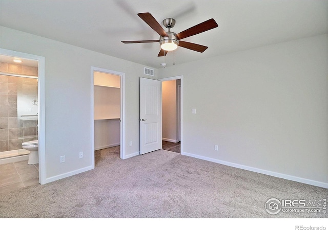 unfurnished bedroom with connected bathroom, a spacious closet, ceiling fan, light colored carpet, and a closet