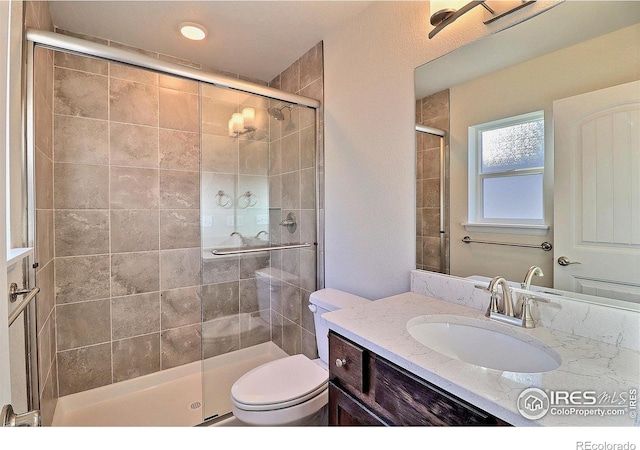 bathroom featuring vanity, toilet, and a shower with door