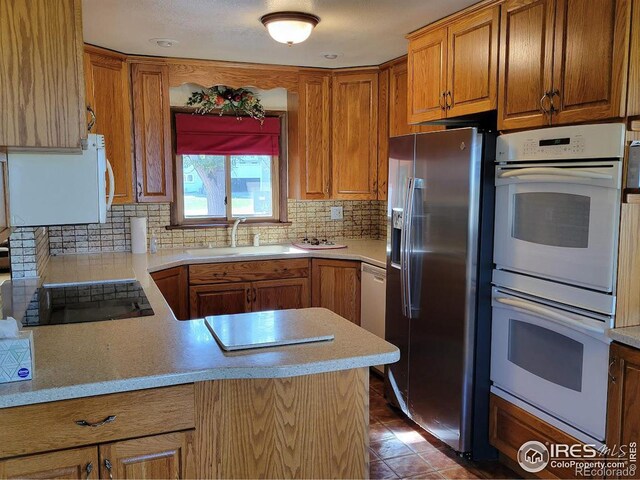 kitchen with black electric cooktop, light tile patterned floors, sink, double oven, and stainless steel fridge