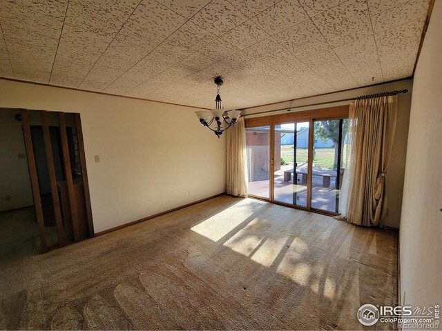 carpeted empty room featuring a chandelier