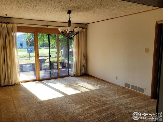 carpeted empty room featuring an inviting chandelier