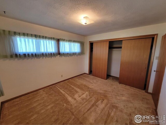 unfurnished bedroom with carpet flooring, a closet, and multiple windows