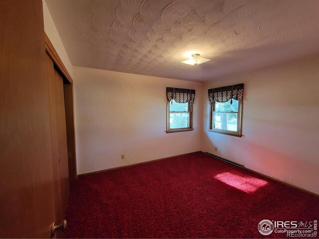 carpeted empty room with baseboard heating and a textured ceiling