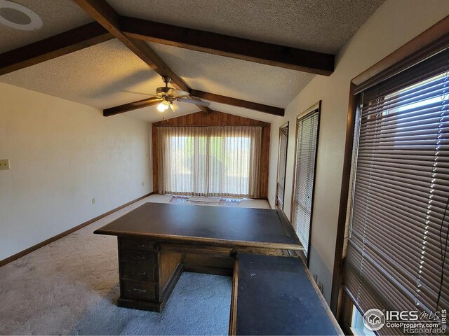 unfurnished office featuring a textured ceiling, lofted ceiling with beams, carpet, and ceiling fan