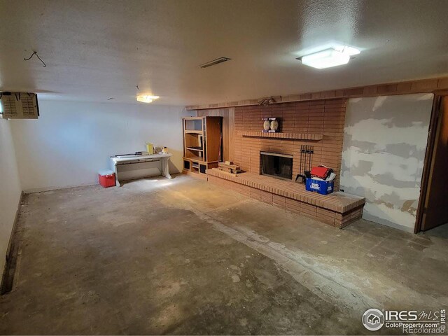 basement with a fireplace, a textured ceiling, and brick wall