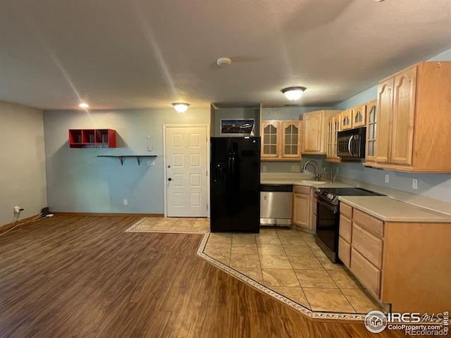 kitchen featuring black appliances, light brown cabinets, sink, and light hardwood / wood-style flooring