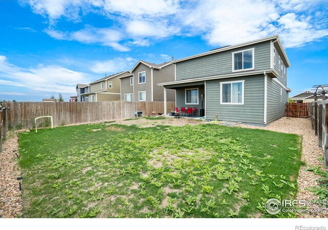 rear view of property featuring a patio area and a yard