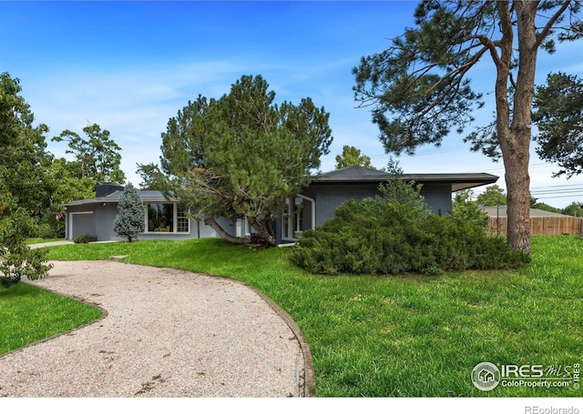 view of front of house featuring brick siding, a front yard, driveway, an attached garage, and fence