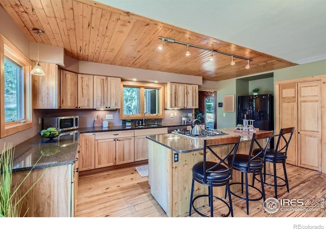 kitchen with a kitchen island, appliances with stainless steel finishes, sink, and light hardwood / wood-style floors