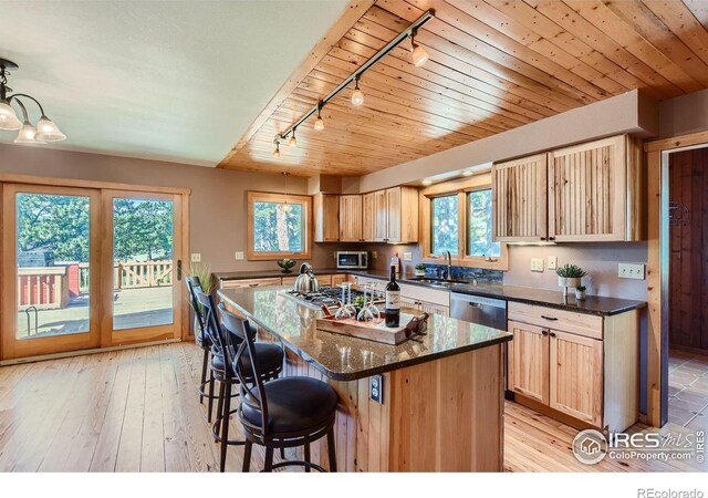 kitchen with sink, a kitchen island, decorative light fixtures, stainless steel appliances, and light wood-type flooring