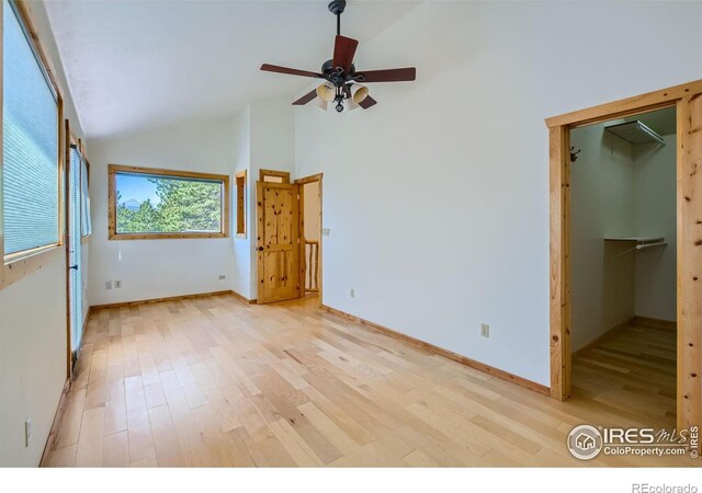 unfurnished bedroom with ceiling fan, light hardwood / wood-style flooring, high vaulted ceiling, and a walk in closet