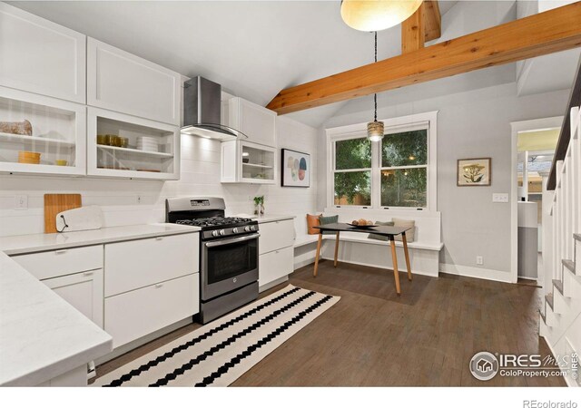 kitchen with dark wood-type flooring, pendant lighting, white cabinets, stainless steel range with gas stovetop, and lofted ceiling with beams