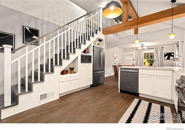 kitchen featuring dark hardwood / wood-style floors, white cabinetry, appliances with stainless steel finishes, hanging light fixtures, and beamed ceiling