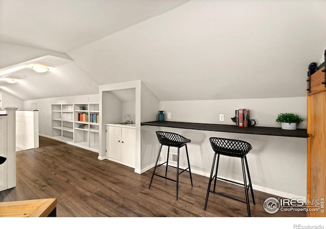 interior space featuring sink, a barn door, dark hardwood / wood-style flooring, and vaulted ceiling