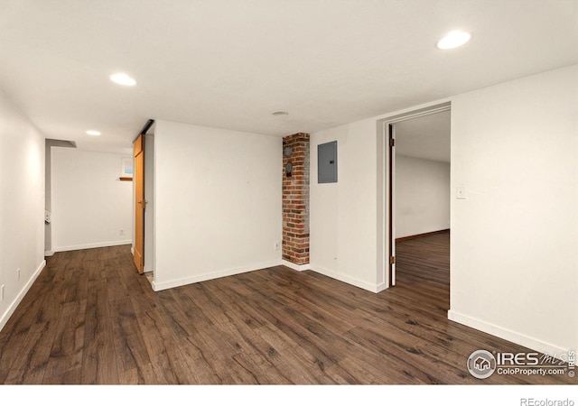 spare room featuring brick wall, electric panel, and dark hardwood / wood-style floors