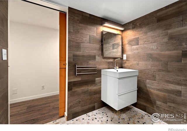 bathroom featuring vanity, wood-type flooring, and tile walls