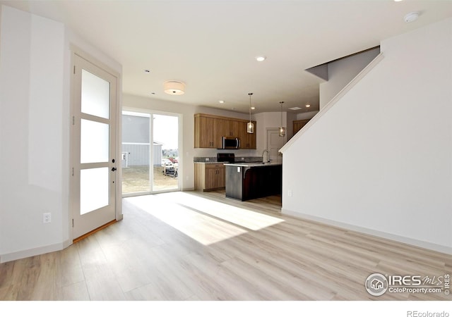 kitchen featuring light wood-type flooring, sink, pendant lighting, and a kitchen island