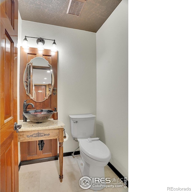 bathroom featuring baseboards, visible vents, toilet, a textured ceiling, and vanity