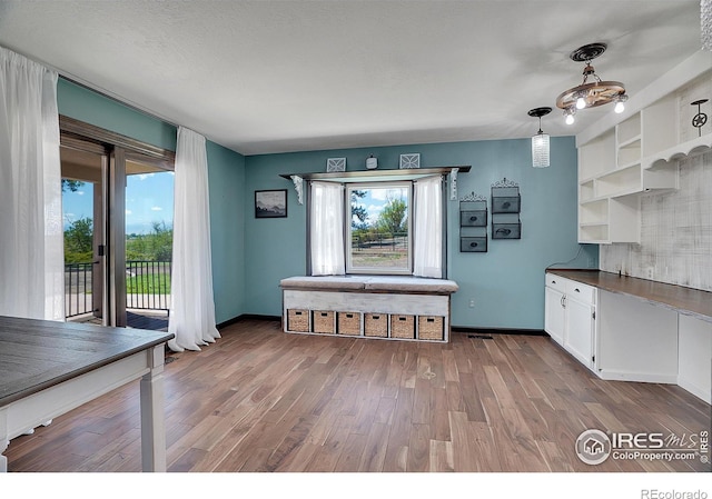 interior space featuring baseboards, white cabinets, dark countertops, wood finished floors, and open shelves