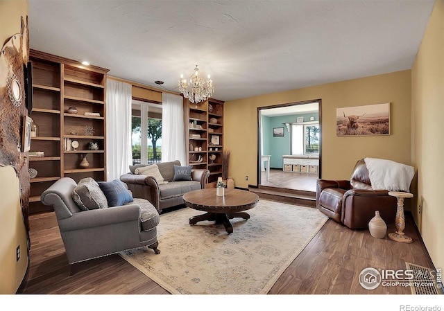 living room with a notable chandelier, wood finished floors, and a healthy amount of sunlight