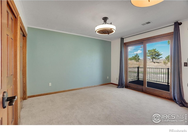 carpeted empty room featuring ornamental molding, visible vents, and baseboards