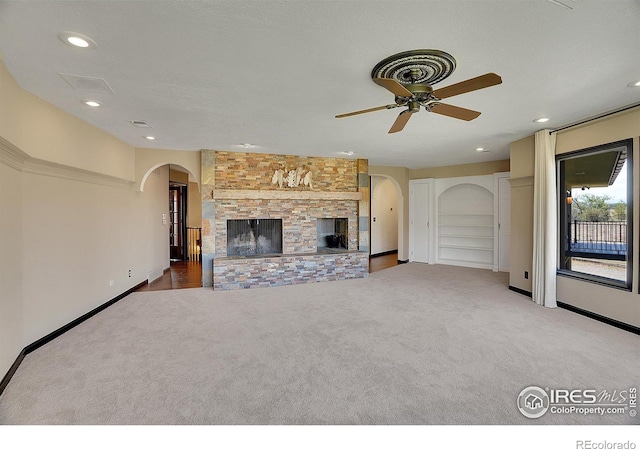 unfurnished living room featuring arched walkways, recessed lighting, carpet floors, a fireplace, and visible vents