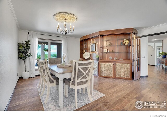 dining space with wood-type flooring, crown molding, and a chandelier