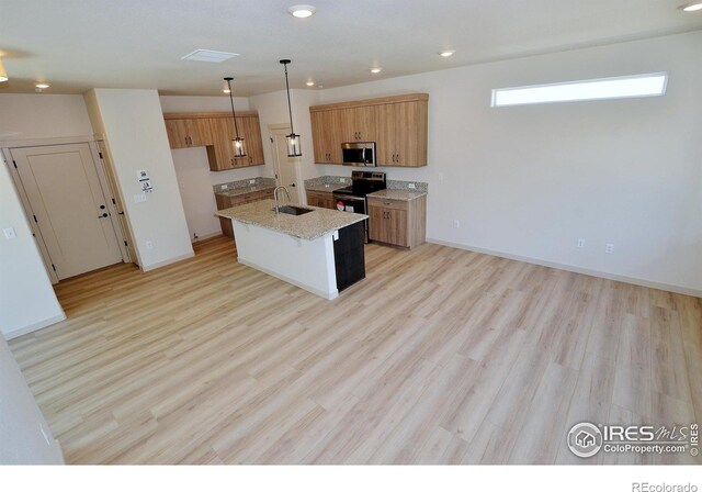 kitchen with light wood-type flooring, pendant lighting, stainless steel appliances, light stone countertops, and sink