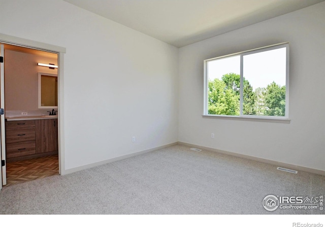 unfurnished bedroom featuring light parquet flooring, sink, and connected bathroom