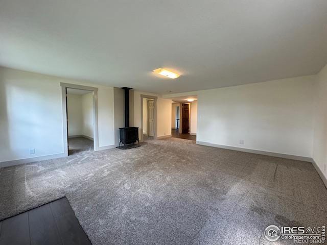 unfurnished living room with carpet floors and a wood stove